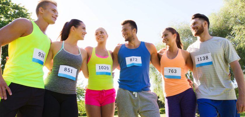 fitness, sport, marathon, friendship and healthy lifestyle concept - group of happy teenage friends or sportsmen couple with racing badge numbers outdoors